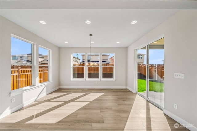 unfurnished dining area with light hardwood / wood-style floors and a notable chandelier