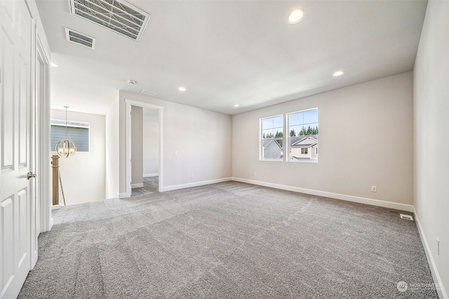 carpeted spare room featuring a notable chandelier