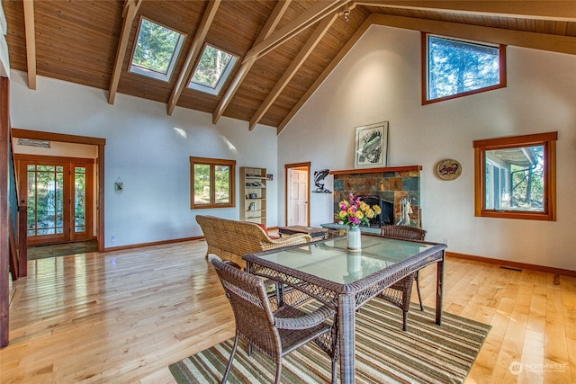 dining space featuring a skylight, beam ceiling, and light wood-type flooring