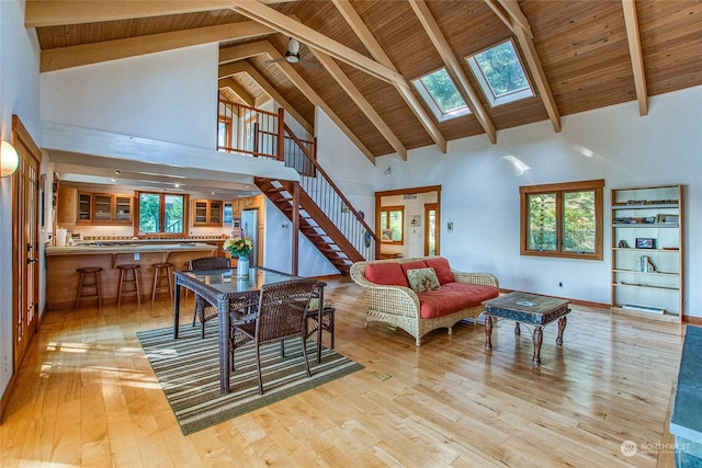 living room featuring a skylight, stairway, wooden ceiling, and light wood-style floors