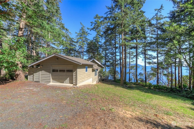 view of side of property featuring a garage, a yard, driveway, and an outdoor structure