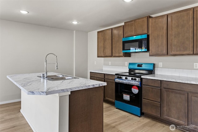 518 Chinook Winds Ln, Tieton, WA 98947 - kitchen featuring a sink, a center island with sink, light wood-style flooring, light countertops, and stainless steel range with electric cooktop