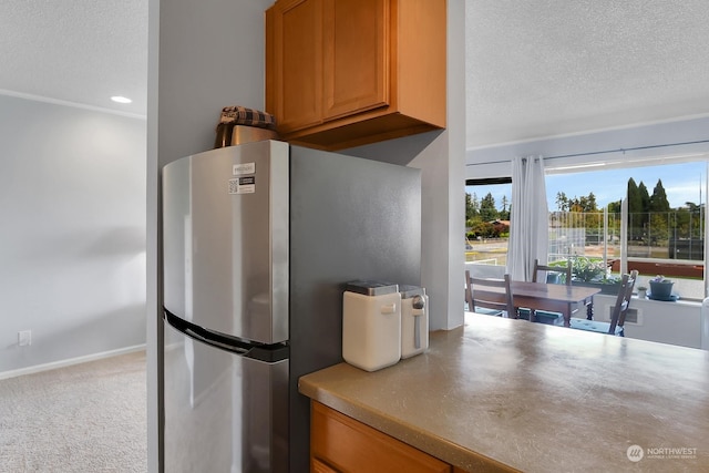 kitchen featuring a textured ceiling, light colored carpet, and stainless steel refrigerator