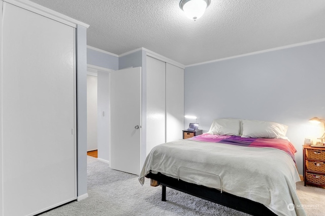 carpeted bedroom with crown molding, a textured ceiling, and a closet