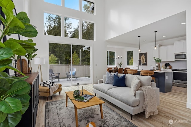 living room featuring a towering ceiling, light hardwood / wood-style flooring, and a chandelier