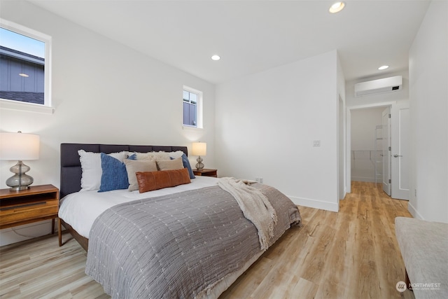 bedroom featuring an AC wall unit, a spacious closet, and light hardwood / wood-style flooring