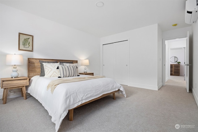 bedroom with an AC wall unit, light carpet, and a closet