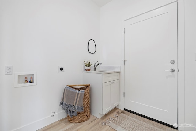 clothes washing area with washer hookup, electric dryer hookup, light hardwood / wood-style flooring, cabinets, and sink