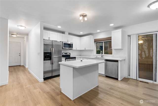 kitchen featuring appliances with stainless steel finishes, light hardwood / wood-style flooring, white cabinetry, and a kitchen island