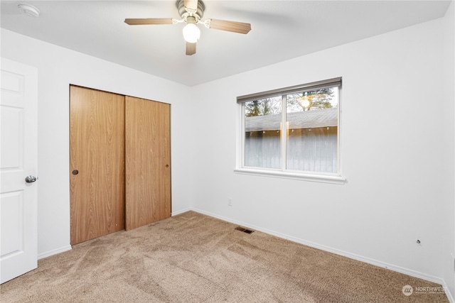 unfurnished bedroom with light carpet, a closet, and ceiling fan