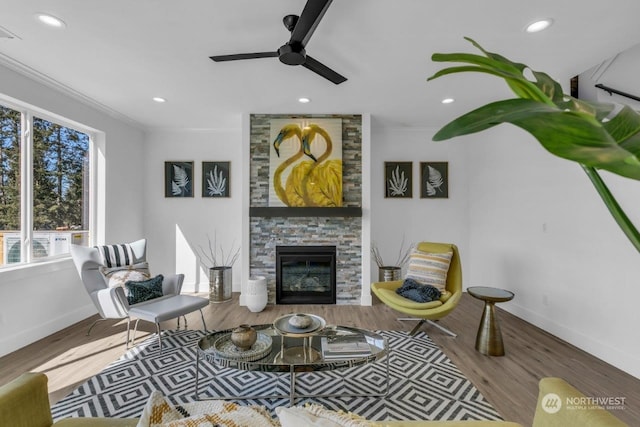 living room featuring ornamental molding, hardwood / wood-style floors, a fireplace, and ceiling fan