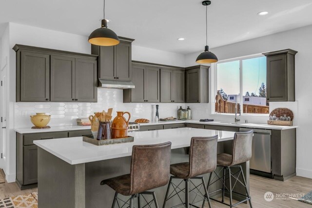 kitchen featuring light hardwood / wood-style flooring, decorative light fixtures, stainless steel dishwasher, and a center island