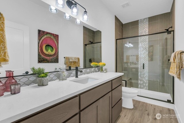 bathroom with walk in shower, vanity, toilet, and hardwood / wood-style floors