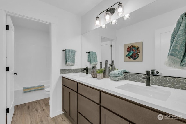 bathroom featuring wood-type flooring, vanity, toilet, and tasteful backsplash