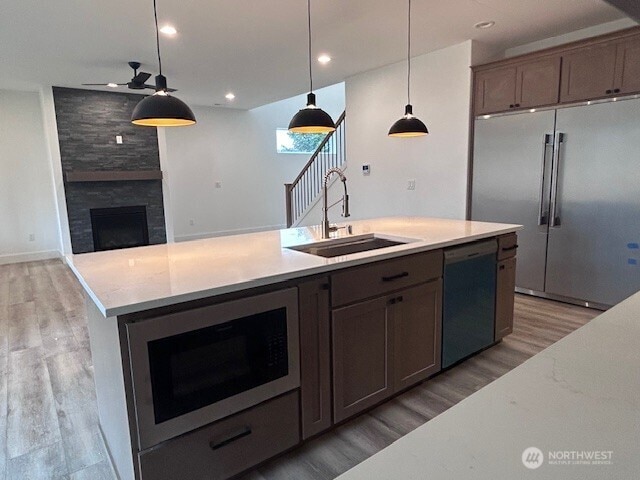 kitchen with a large fireplace, built in microwave, dishwashing machine, high end fridge, and a sink