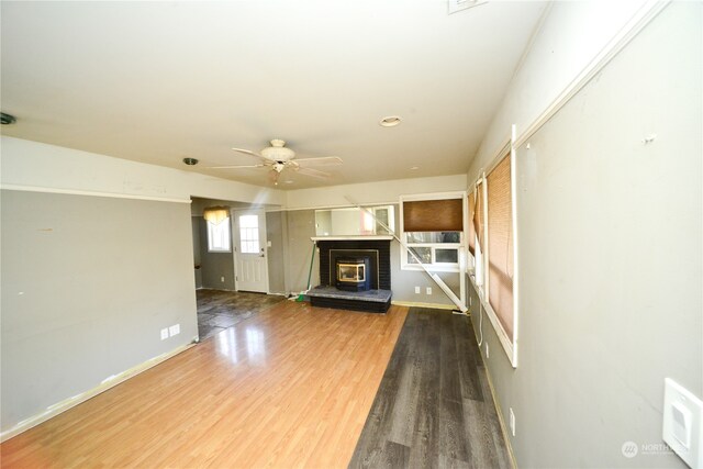 unfurnished living room with a fireplace, wood-type flooring, and ceiling fan