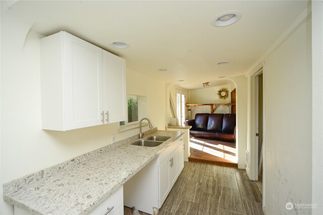 kitchen featuring light stone countertops, sink, white cabinetry, and hardwood / wood-style flooring