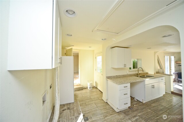 kitchen with light stone countertops, sink, white cabinetry, and light hardwood / wood-style floors