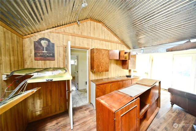 kitchen with wood-type flooring, lofted ceiling, and wooden walls