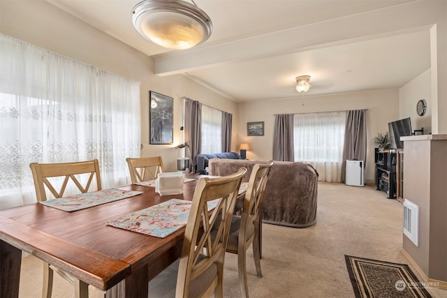 carpeted dining area featuring beam ceiling and a wealth of natural light