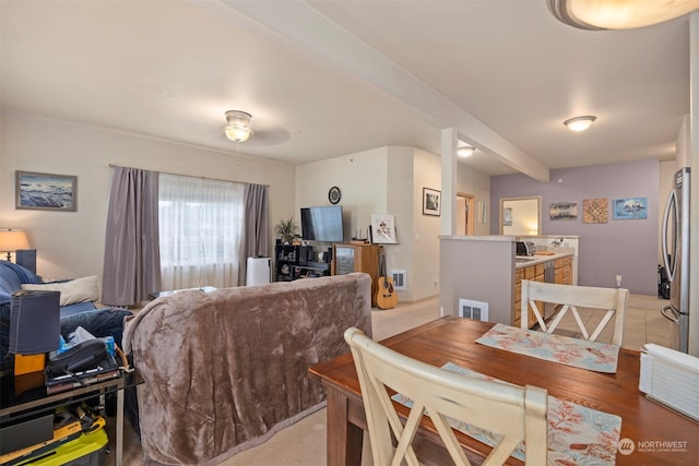 carpeted dining area with beam ceiling