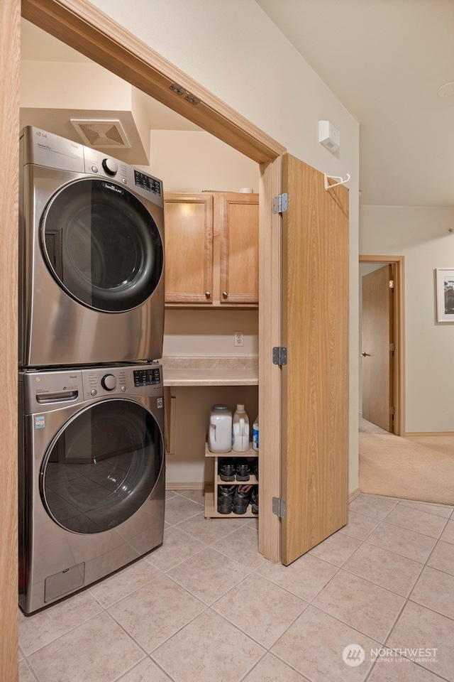 clothes washing area with stacked washer and clothes dryer and light tile patterned floors