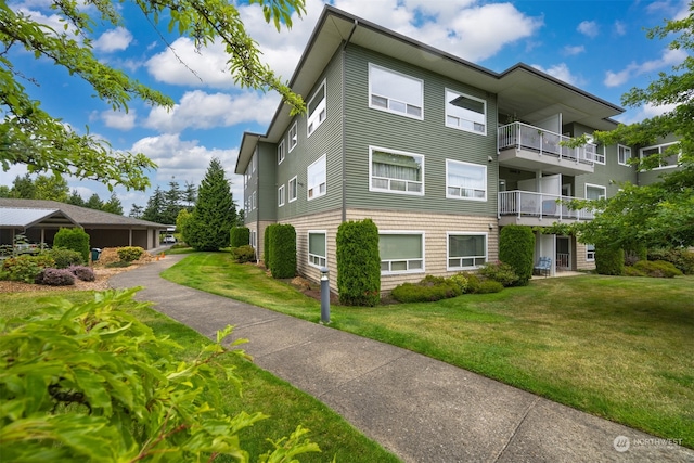 view of home's exterior featuring a balcony and a yard