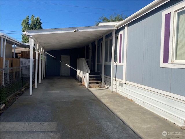 view of property exterior with an attached carport, concrete driveway, and fence