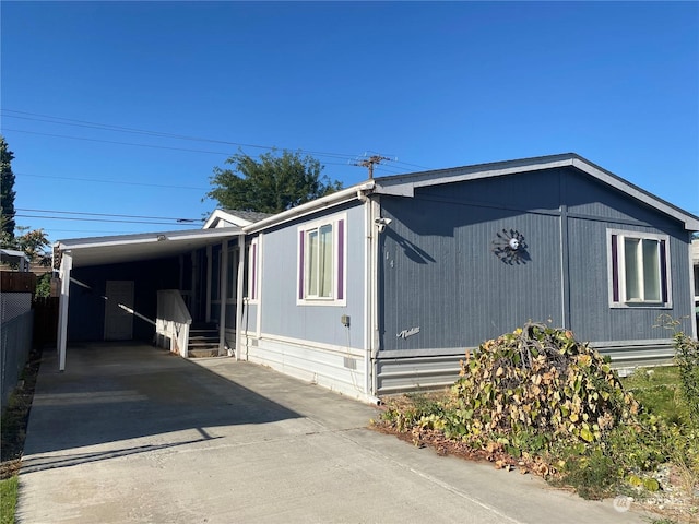 view of side of home with driveway, an attached carport, and fence