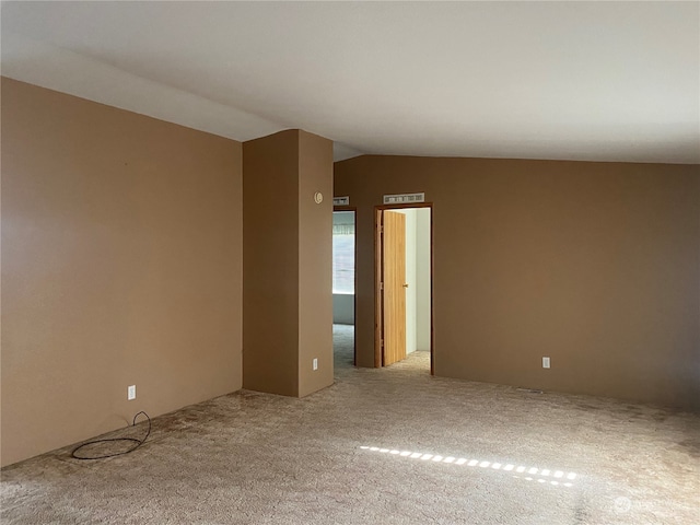 spare room featuring light carpet and vaulted ceiling