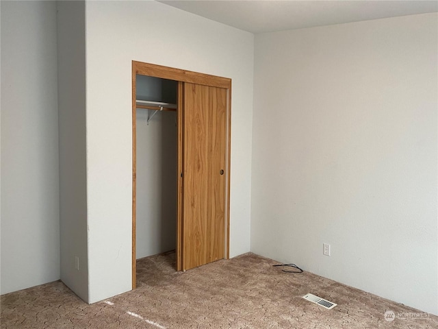 unfurnished bedroom featuring light carpet, visible vents, and a closet