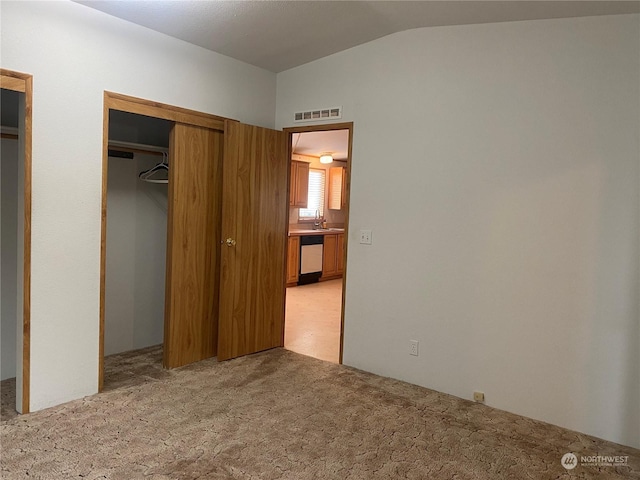 unfurnished bedroom featuring light carpet, vaulted ceiling, a sink, and visible vents