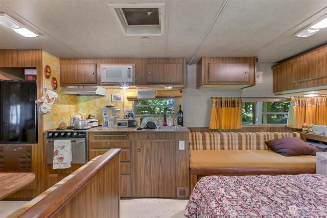 kitchen with black refrigerator, gas range, and a textured ceiling