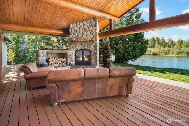 wooden terrace featuring a water view, a yard, and an outdoor stone fireplace