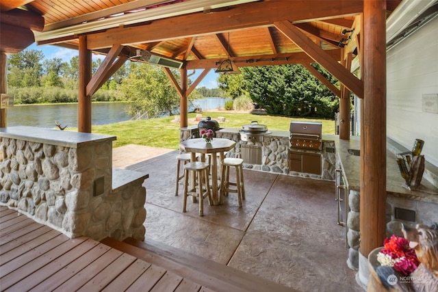 exterior space with exterior kitchen, a grill, a gazebo, and a water view