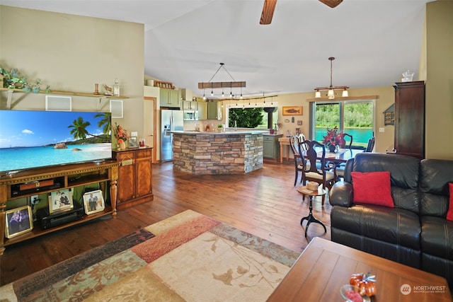 living room with ceiling fan with notable chandelier, vaulted ceiling, and dark hardwood / wood-style flooring