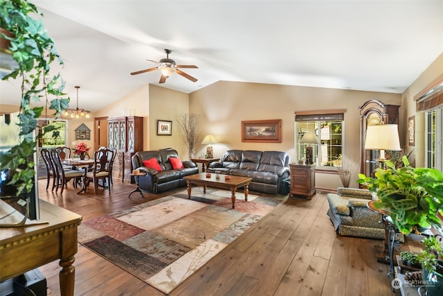 living room with vaulted ceiling, ceiling fan with notable chandelier, and hardwood / wood-style flooring