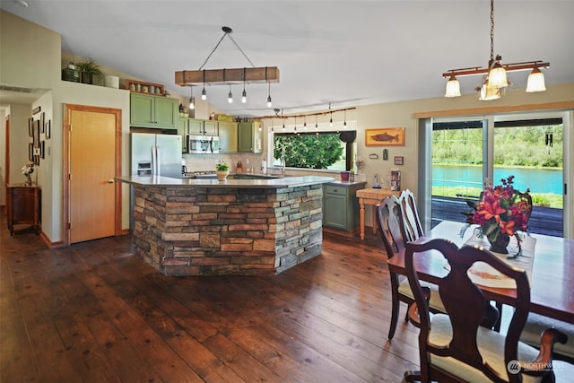 kitchen with pendant lighting, appliances with stainless steel finishes, green cabinets, a center island, and dark wood-type flooring