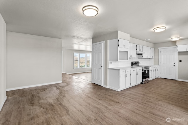 kitchen featuring light wood-type flooring, stainless steel electric range oven, backsplash, and white cabinets