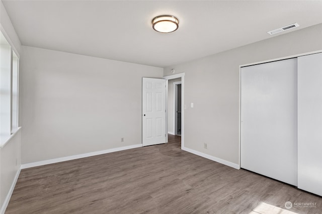 unfurnished bedroom with a closet, multiple windows, and hardwood / wood-style flooring