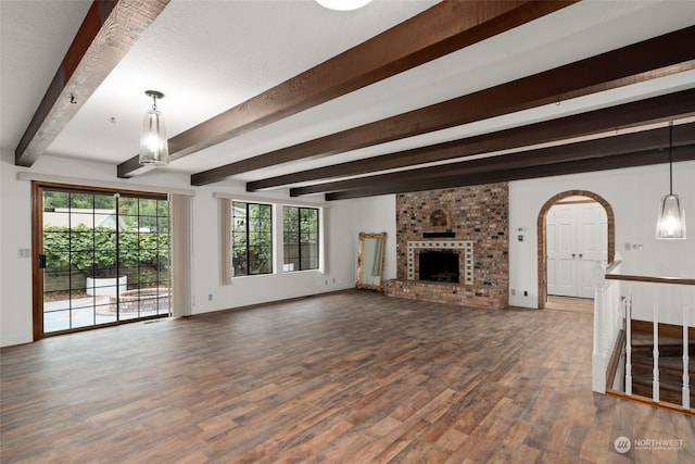 unfurnished living room featuring dark hardwood / wood-style floors, a textured ceiling, beamed ceiling, and a brick fireplace