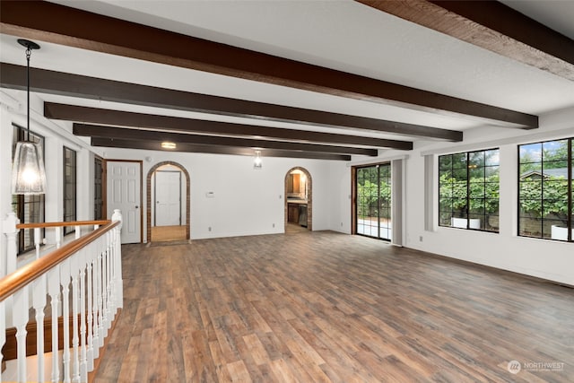 interior space featuring plenty of natural light, beam ceiling, and dark wood-type flooring