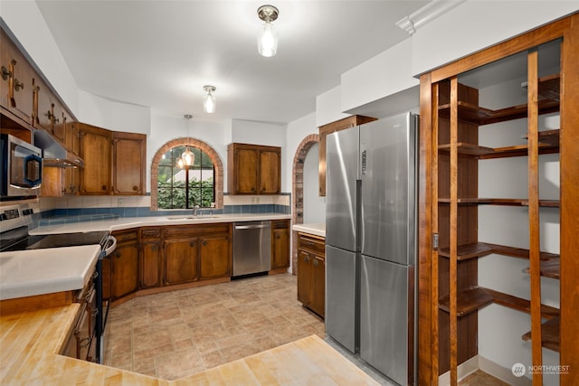 kitchen featuring tasteful backsplash, stainless steel appliances, sink, and hanging light fixtures