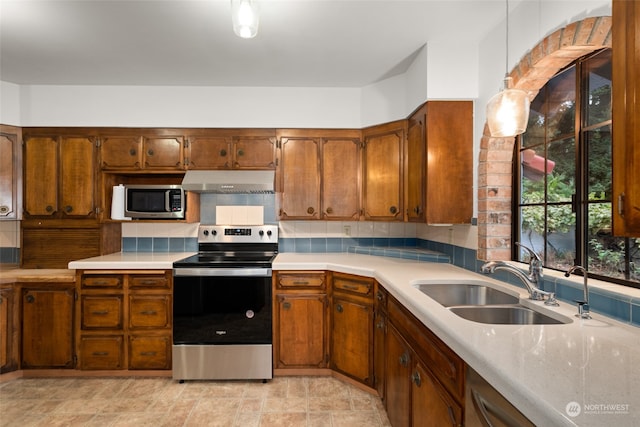 kitchen with pendant lighting, stainless steel appliances, sink, and tasteful backsplash