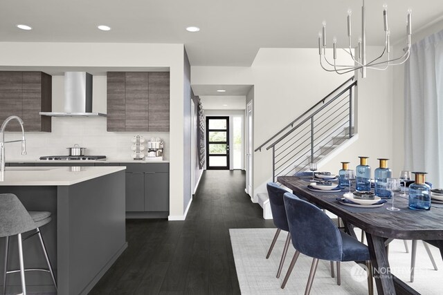 kitchen with tasteful backsplash, a chandelier, a kitchen bar, dark hardwood / wood-style flooring, and wall chimney range hood