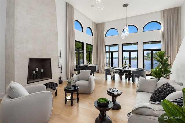 living room featuring a towering ceiling, a water view, and light hardwood / wood-style flooring