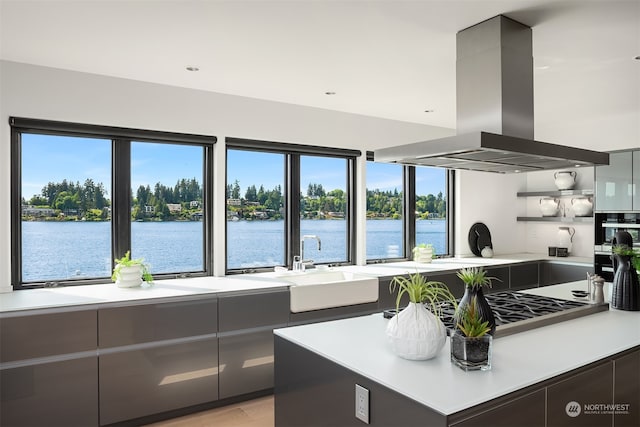 kitchen featuring island exhaust hood, plenty of natural light, a water view, and sink