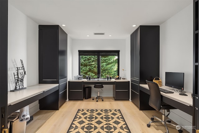 office space with built in desk and light hardwood / wood-style floors