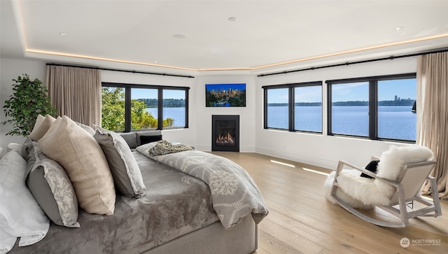 bedroom with light hardwood / wood-style flooring and a water view