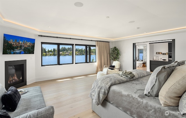 bedroom with a water view and light hardwood / wood-style floors